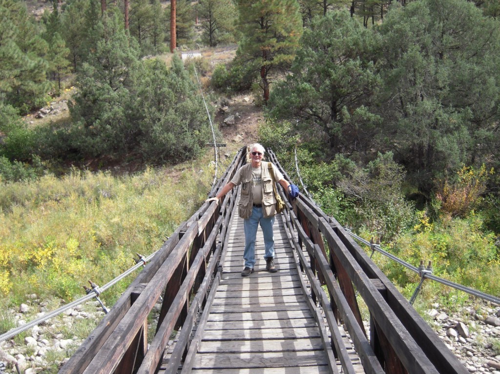 Photograph of the author standing in the middle of a wooden walking bridge, smiling.